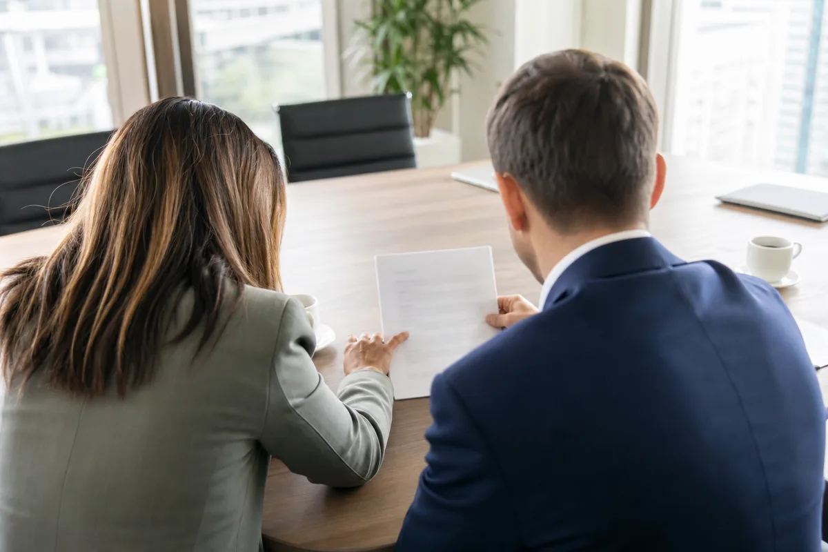 Dirigeant de PME et salariée examinant un contrat de complémentaire santé au bureau